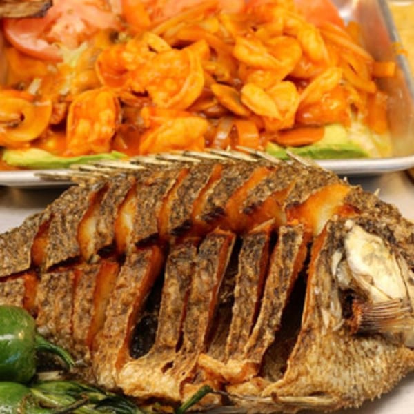 Whole fried fish with sliced green peppers and a dish of shrimp in red sauce.