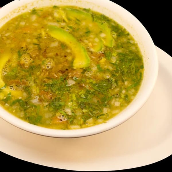 Close-up of a bowl of La Parrilla Taqueria's Mexican soup with avocado slices, cilantro, and onions.