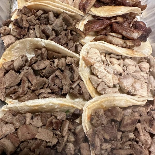 Close-up of several La Parrilla Taqueria Mexican street tacos filled with various meats.