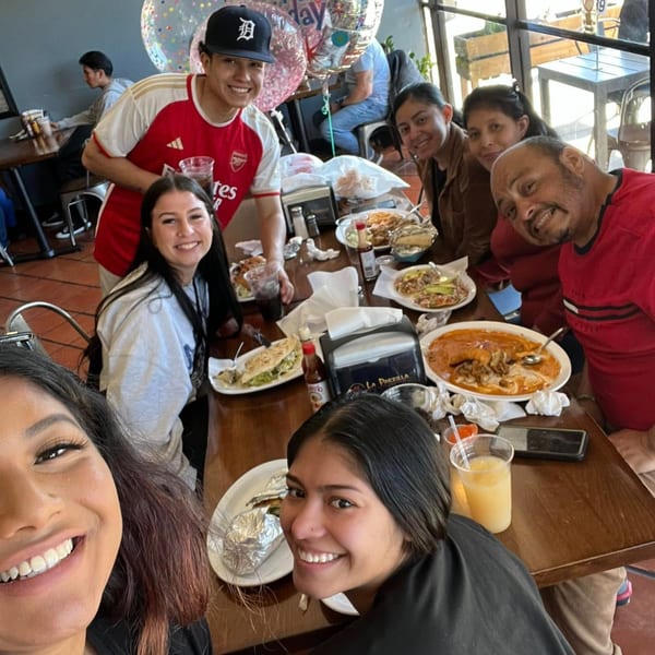 A group of happy people gathered around a table filled with Mexican food and drinks at La Parrilla Taqueria.