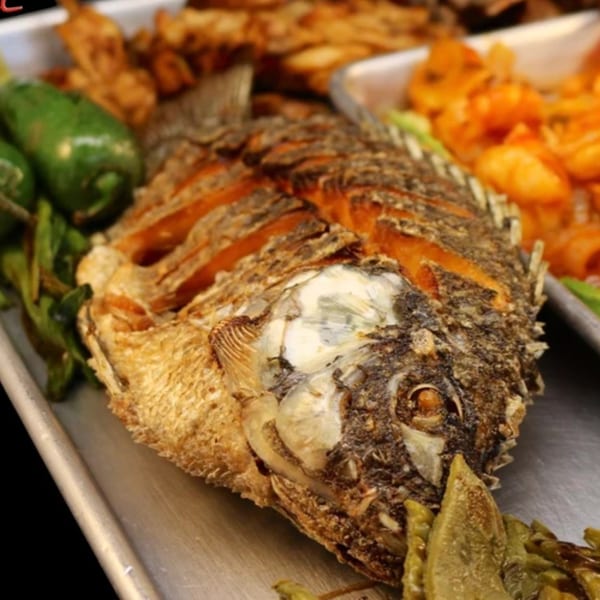 Whole fried fish with crispy skin, served with green peppers and other Mexican dishes.