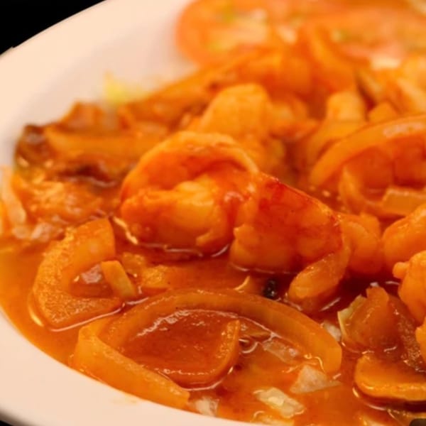 Close-up of La Parrilla Taqueria's camarones a la diabla, featuring shrimp and onions in a spicy red sauce.