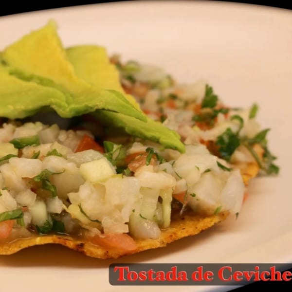 La Parrilla Taqueria's Tostada de Ceviche, topped with fresh avocado slices on a white plate.
